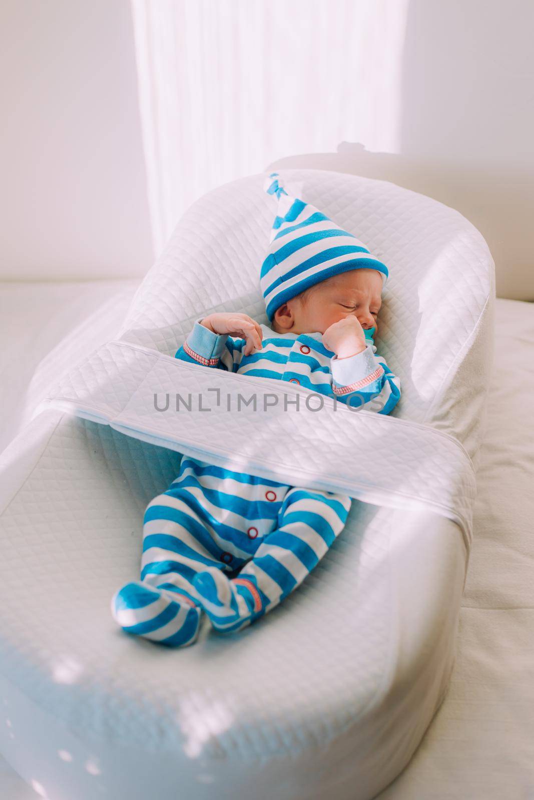 The baby is lying in a cocoon of copy space . The baby is 0-3 months old. A contented infant. An article about choosing a cocoon for newborns. An article about the benefits of cocoon. An article about colic .