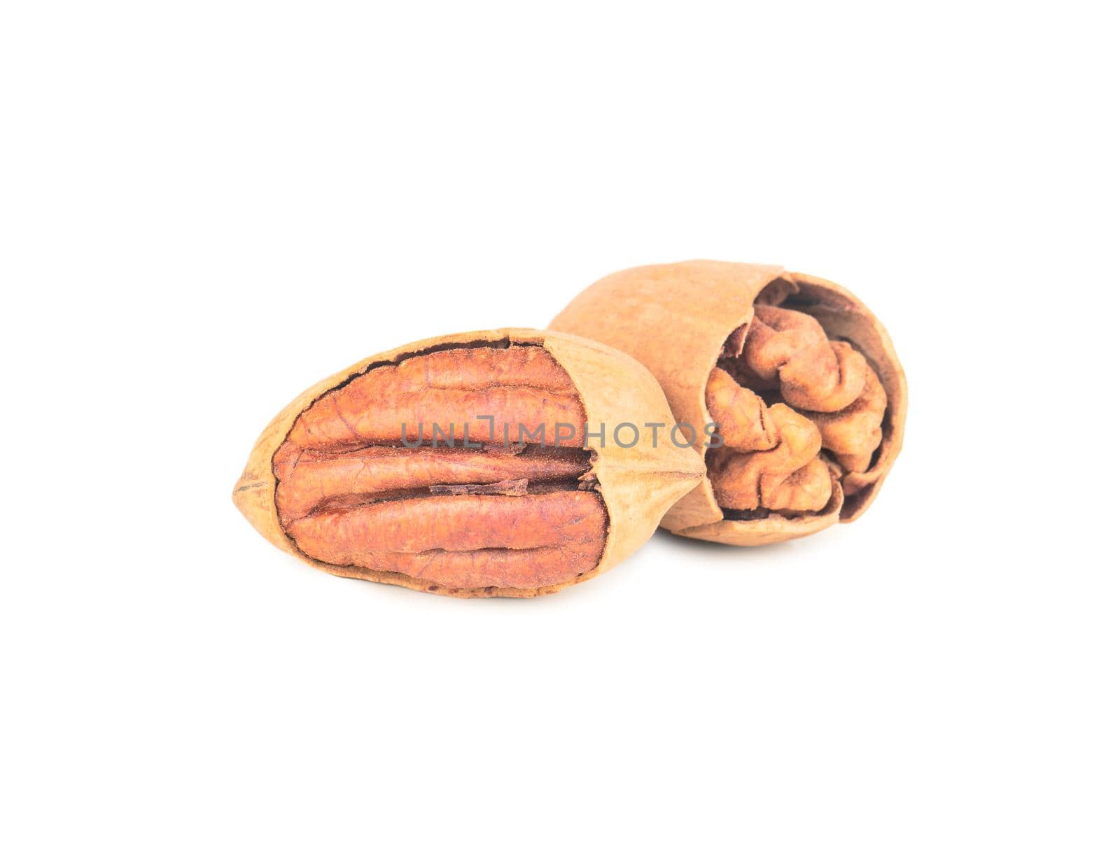 Two dry pecans in cracked shells on a white background