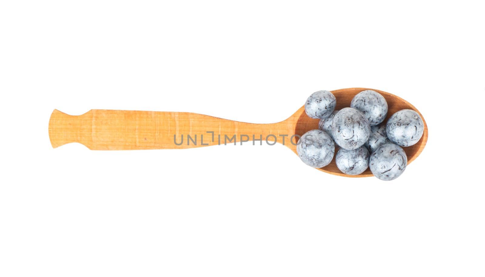 Round chocolate candies in a spoon close-up on a white background, top view