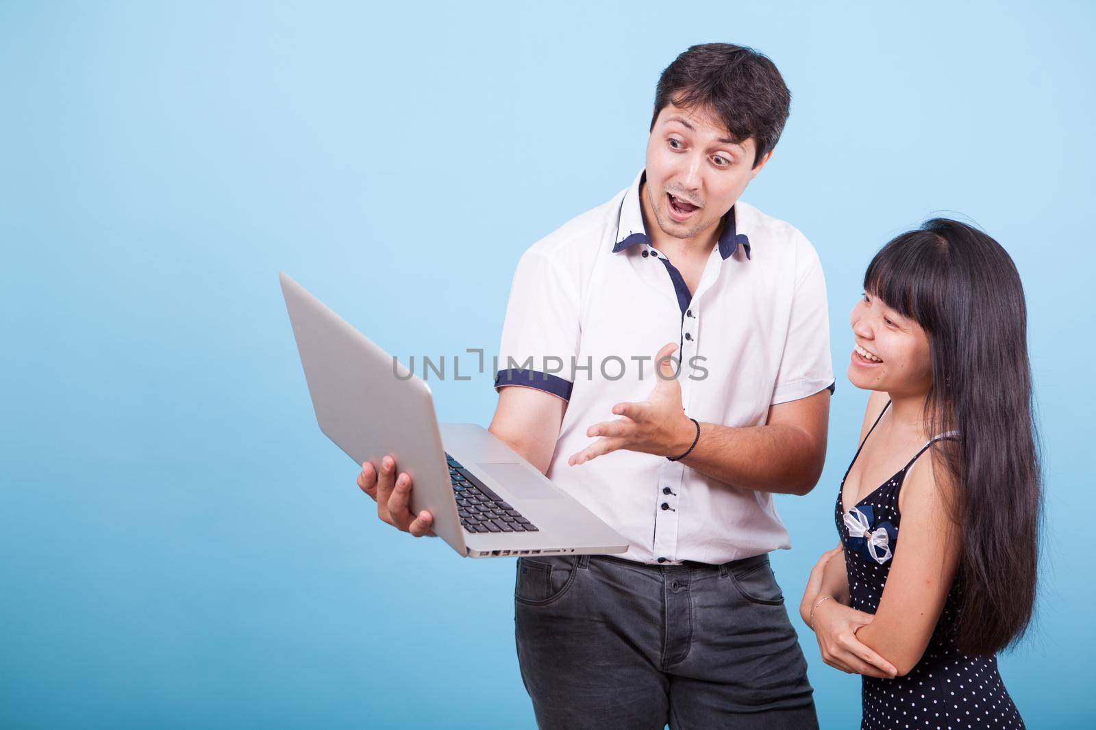 Interracial couple having a video call on laptop in studio. Beautiful interracial couple. Beautiful asian.