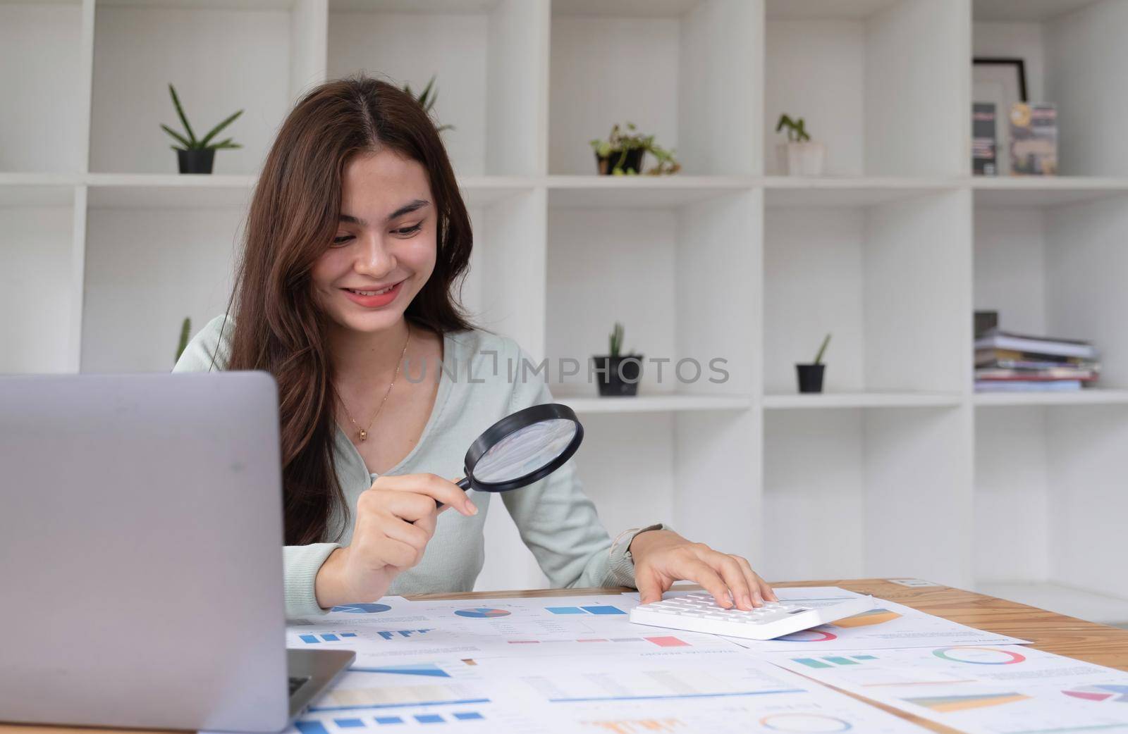 Tax inspector and financial auditor looking through magnifying glass, inspecting company financial papers, documents and reports.