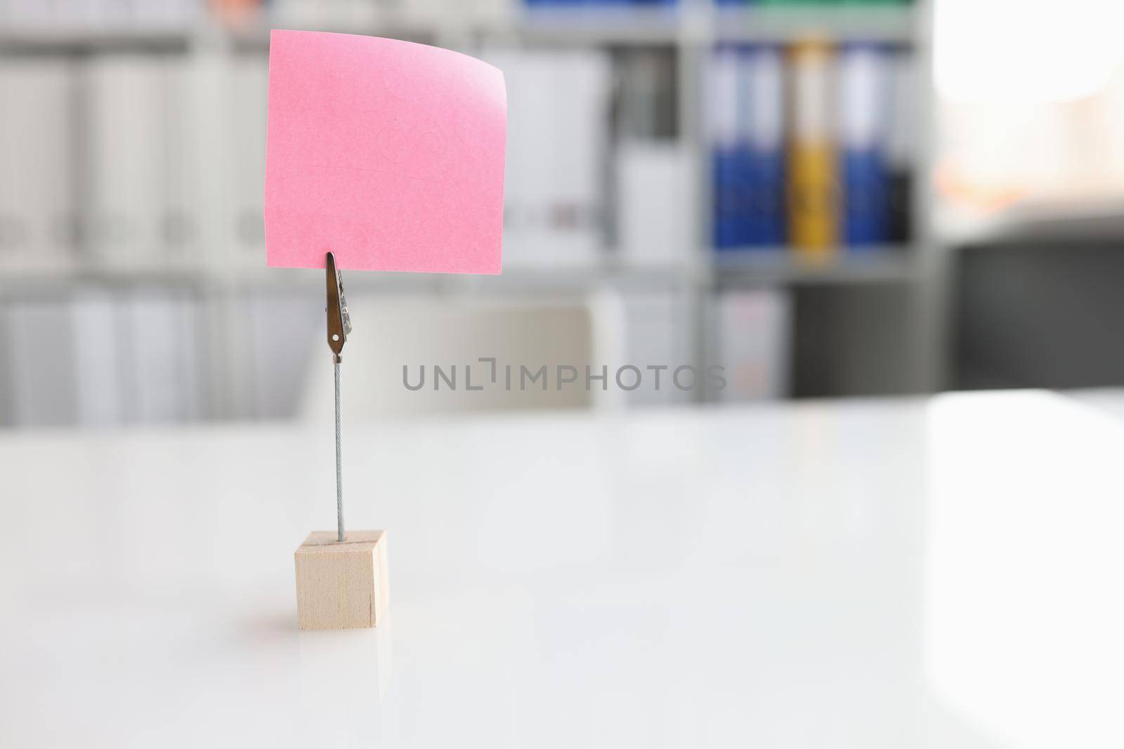 Office desk with pink sticker and paper clip. Business note with copy space