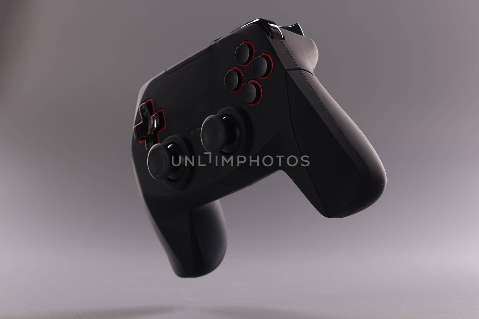 Black plastic wireless gamepad on gray background by kuprevich