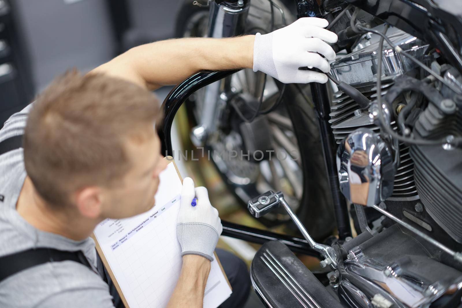 Car mechanic inspects motorcycle breakdowns in car repair shop by kuprevich