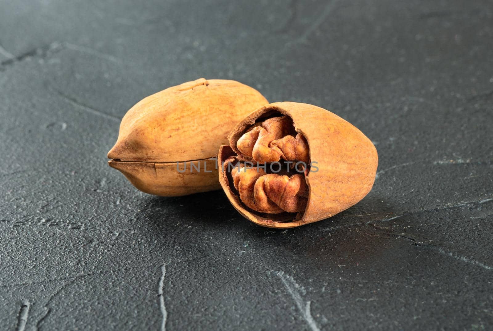 Inshell pecan with split half on dark concrete background