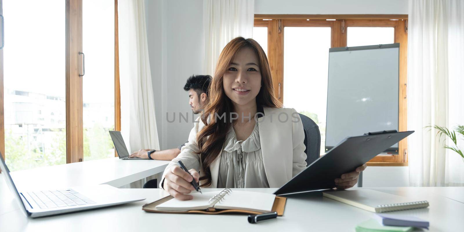 Portrait of an Asian young business Female working on a laptop computer in her workstation.Business people employee freelance online report marketing e-commerce telemarketing concept..