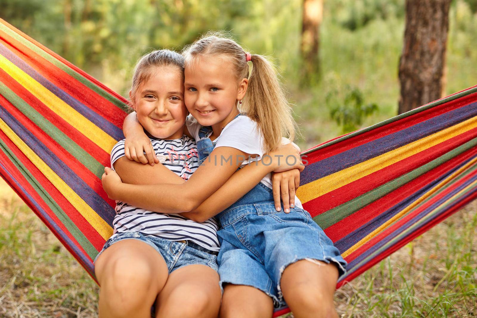 Kids relax in colorful rainbow hammock. cation. Children relaxing. by InnaVlasova