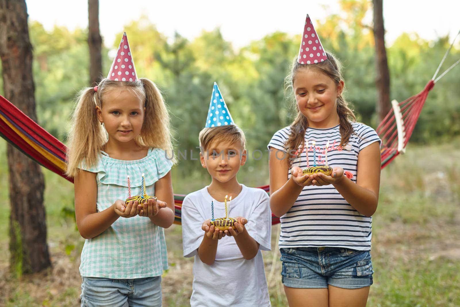 Boy and girls celebrating birthday outdoor in the garden by InnaVlasova