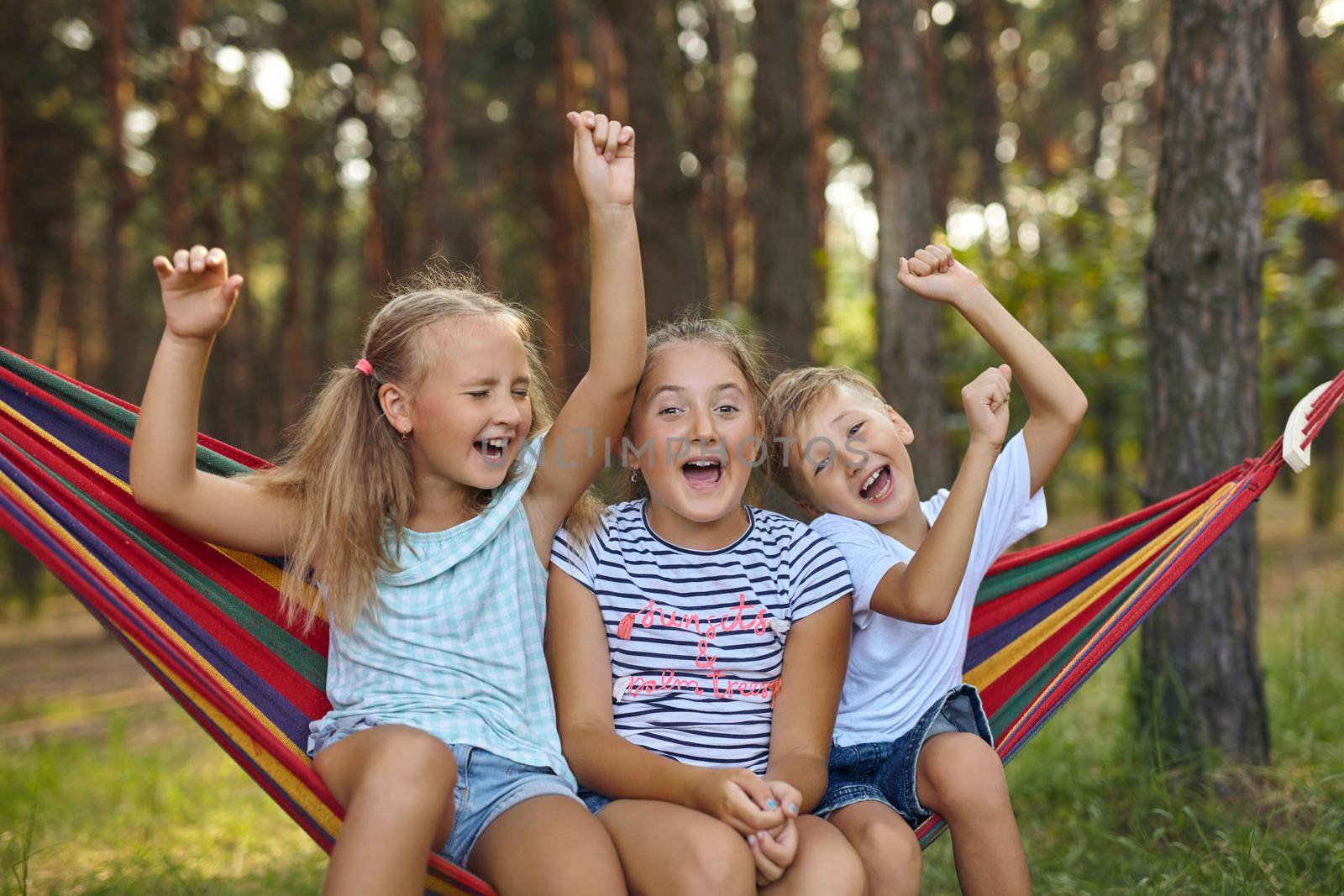 Fun in the garden kids playing in colorful hammock by InnaVlasova