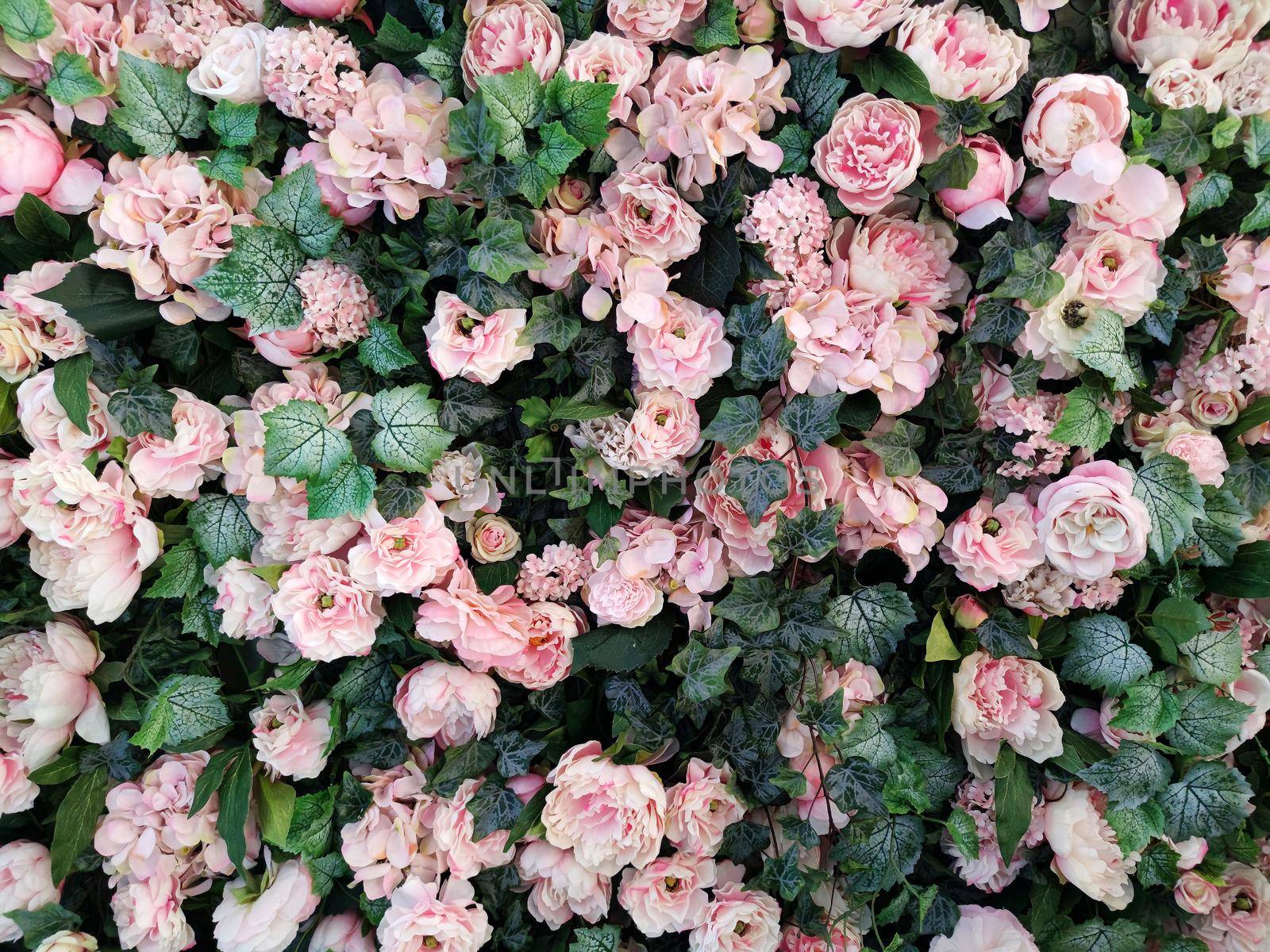 A pattern of green hedera leaves and pastel pink flowers for a delicate plant background.