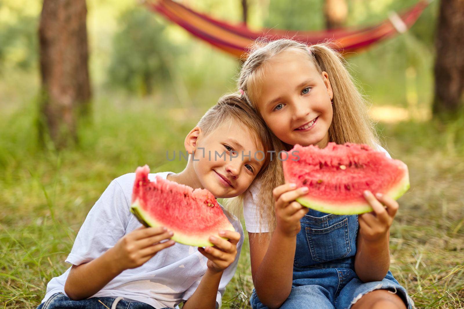 Kids eating watermelon in the park. by InnaVlasova