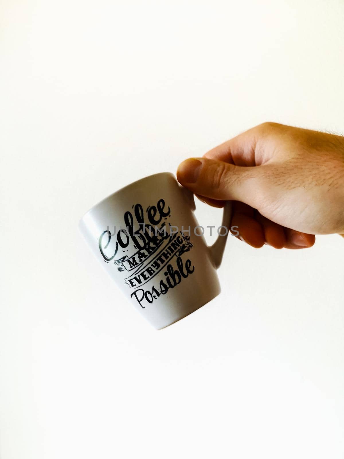 White cup with calligraphy lettering on it coffee makes everything possible holded in hand