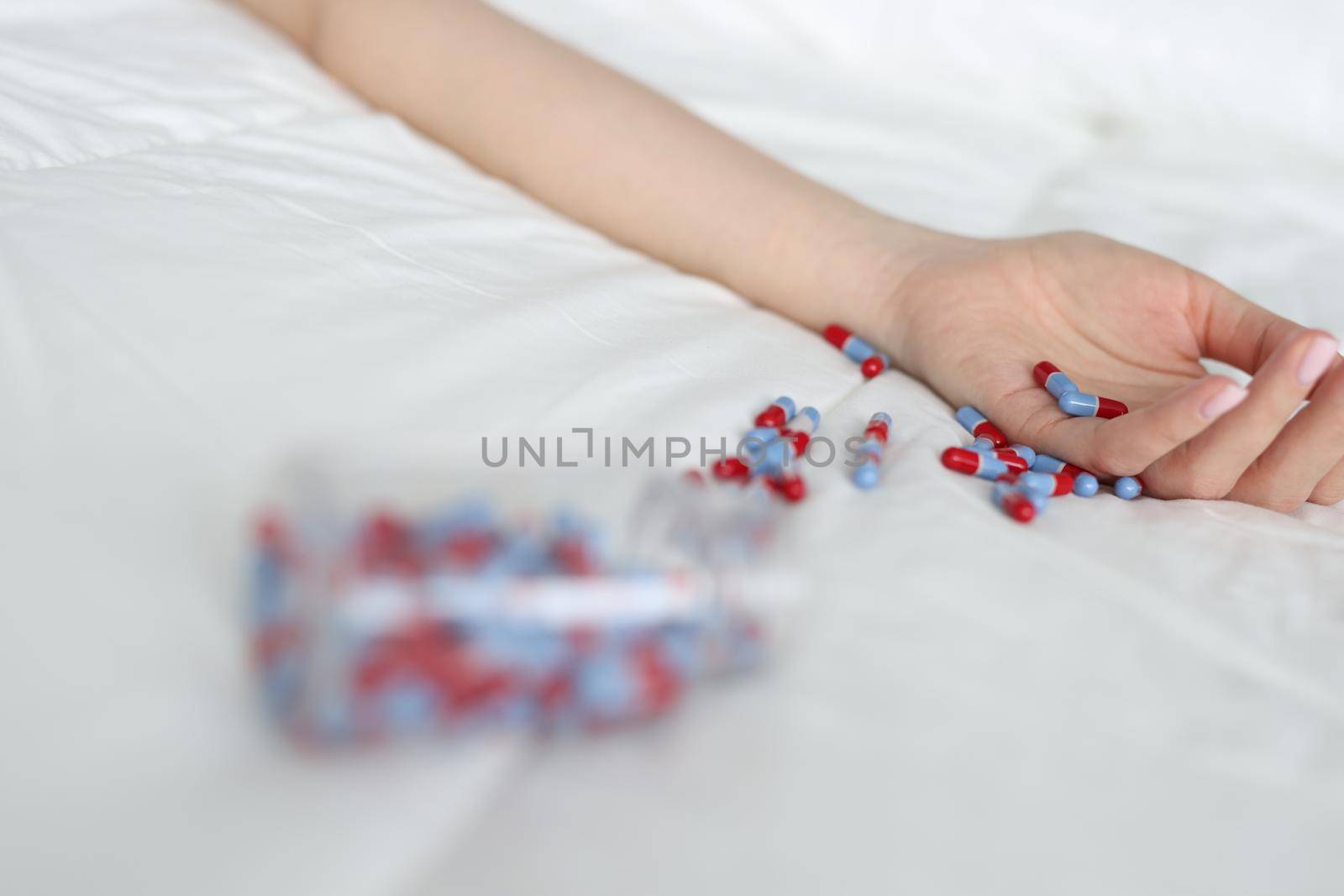 Woman hand after overdose of medical pills on bed. Medical consequences of abuse of sleeping pills concept