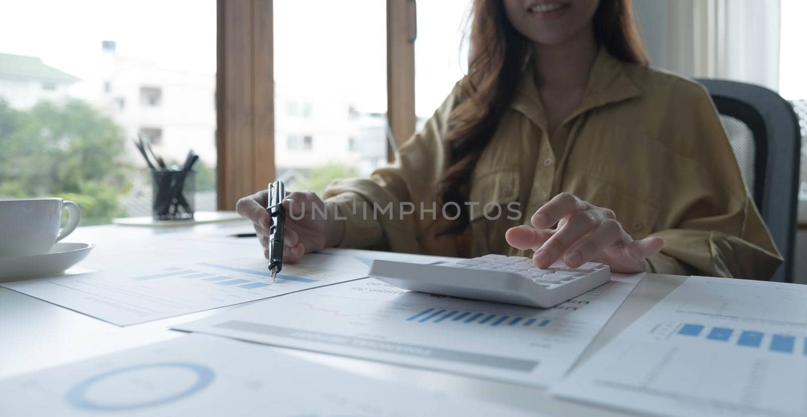 Asian female accountant or banker making calculations. Savings, finances and economy concept through a laptop..