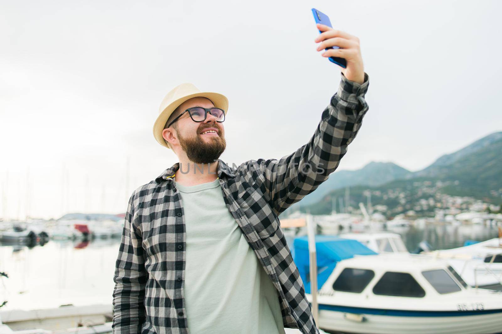 Traveller man taking selfie of luxury yachts marine during sunny day - travel and summer