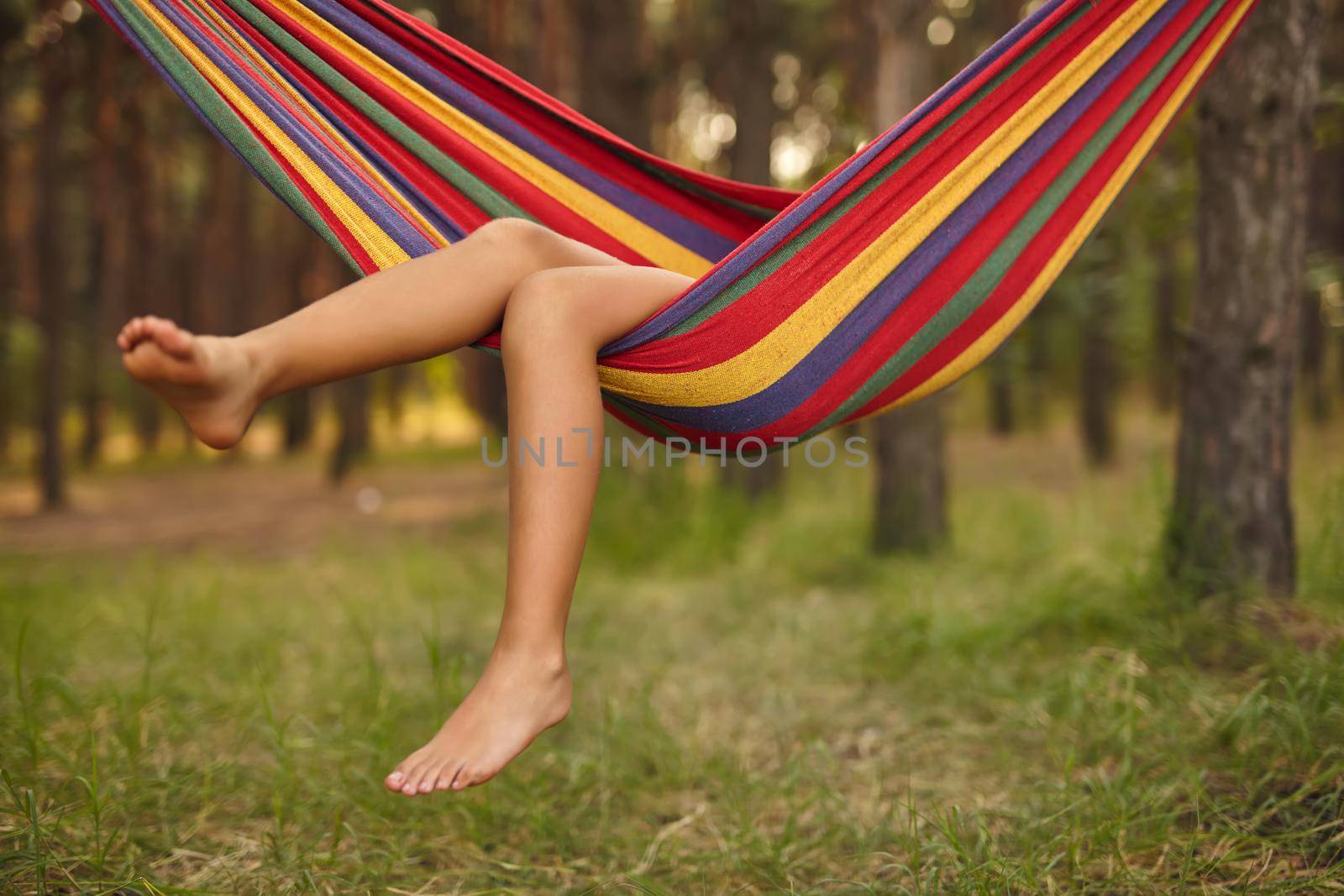 Foot of a child lying in the hammock and relaxing on a sunny day. Bare feet. Lifestyle concept.