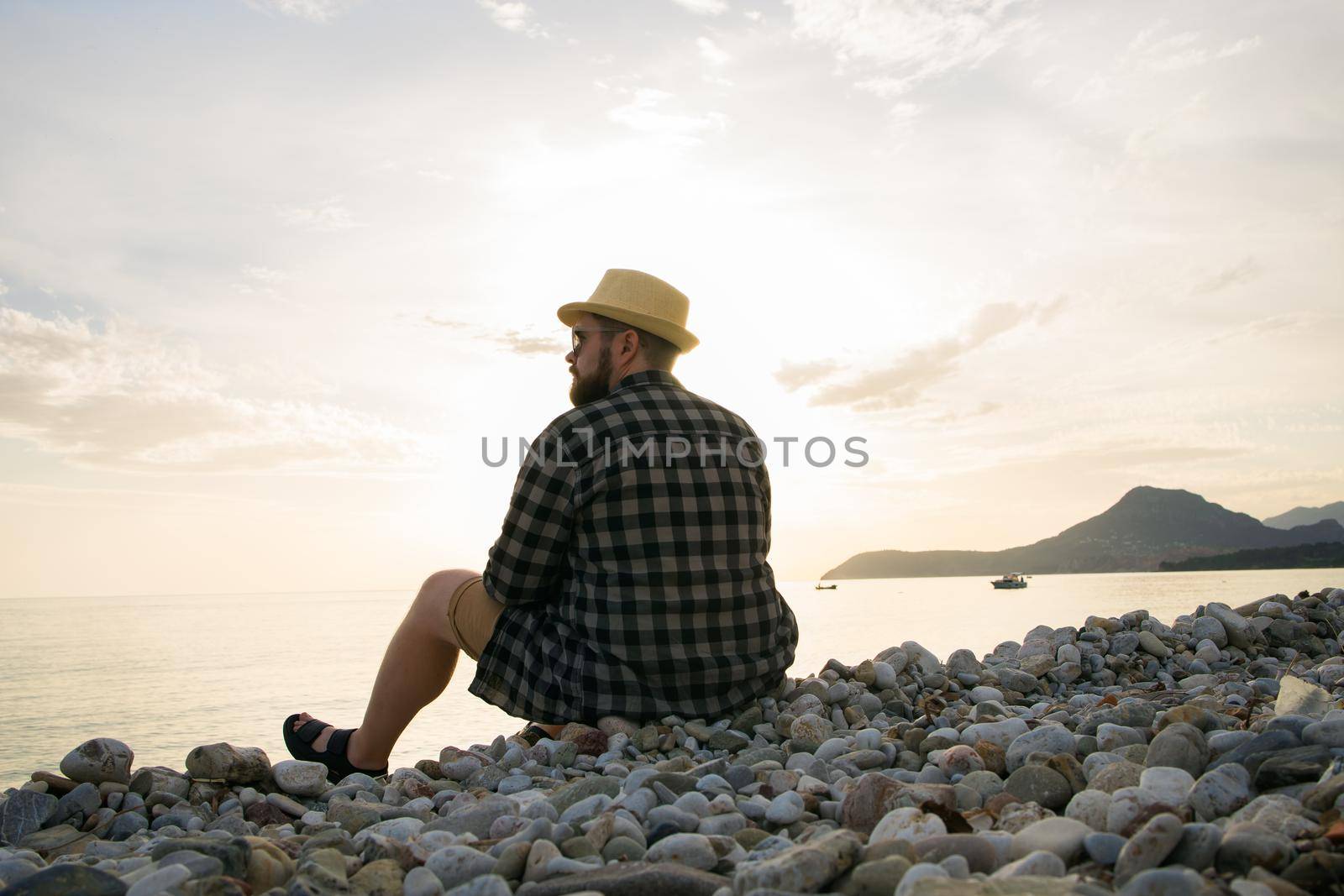 Rear view of man sitting on beach on sunny day outside background - vacation or freelance travel concept by Satura86