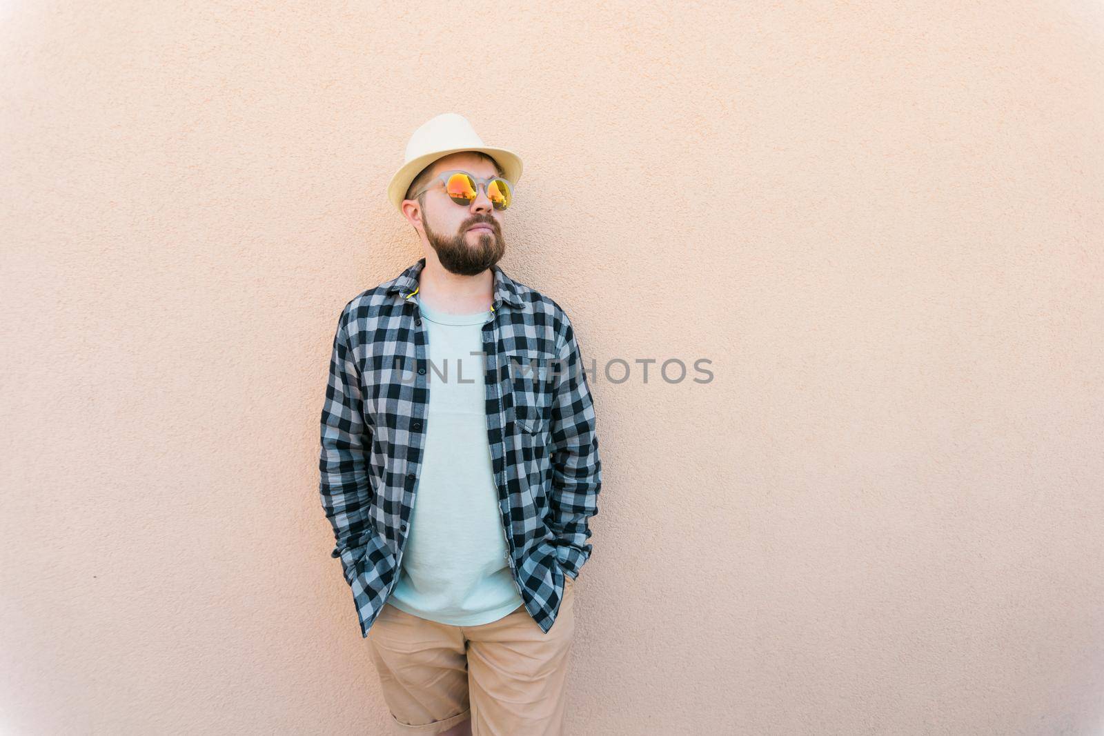 Handsome caucasian man wearing summer hat and plaid shirt smiling happy near wall with copy space - travel vacations and summer holiday concept by Satura86