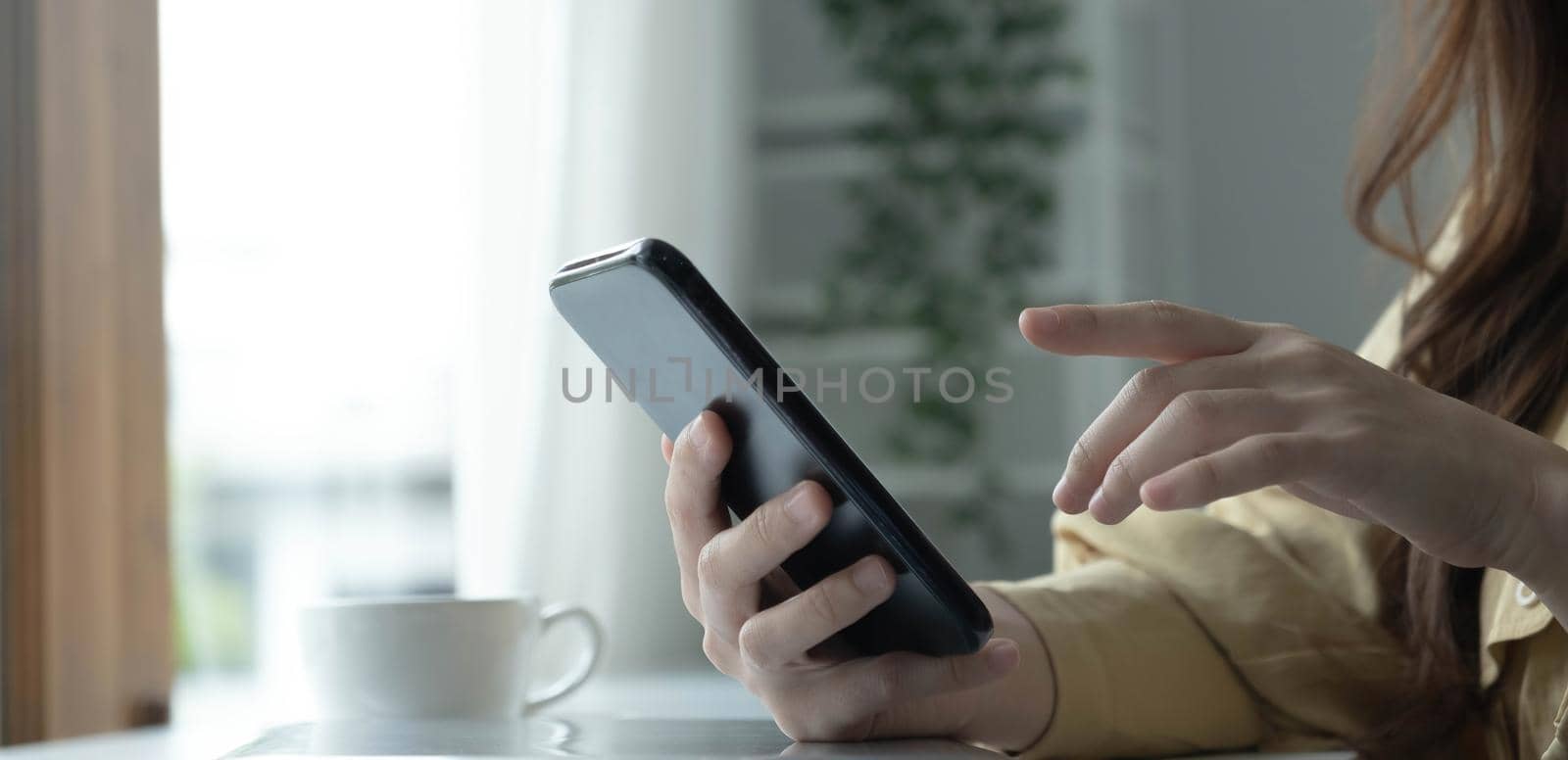 Close up hand of woman using smartphone at coffee shop cafe.