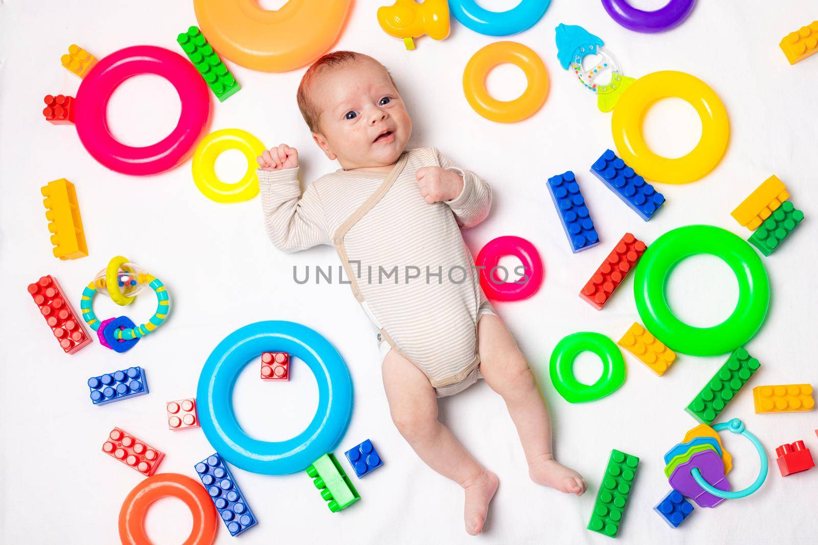 The baby is lying in toys . An article about children's toys. A selection of toys for kids. by alenka2194