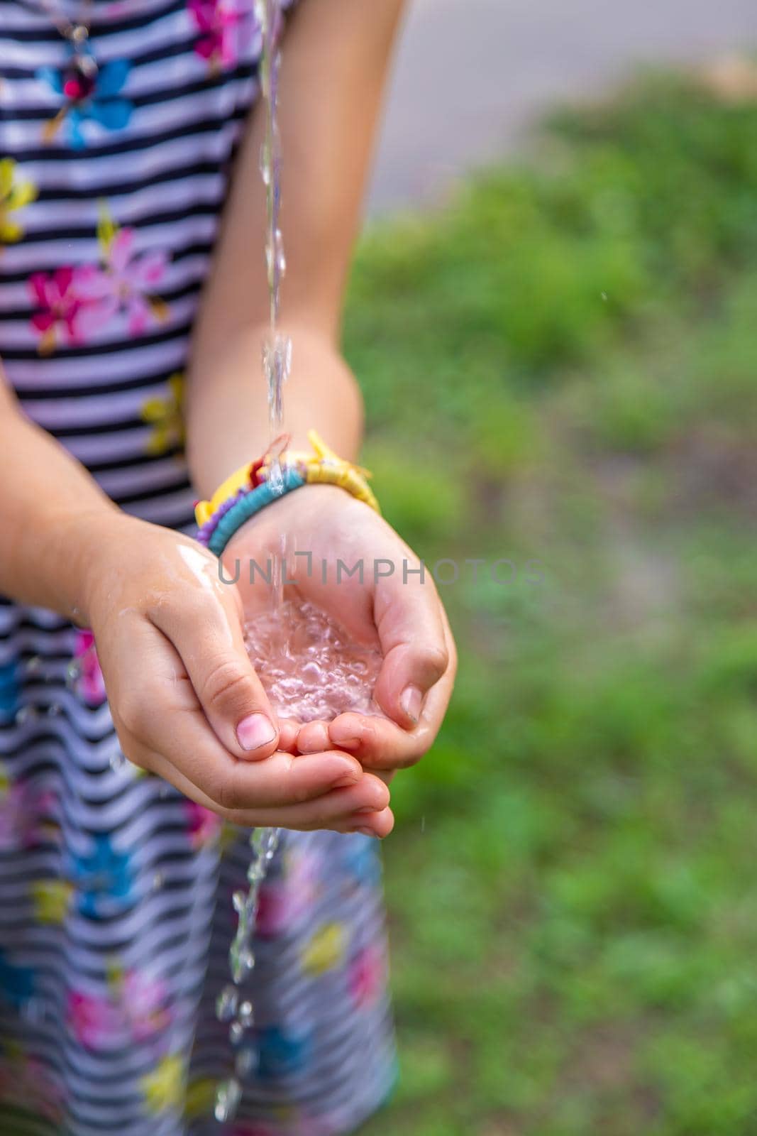 The child drips water into his hands. Selective focus. Kid.
