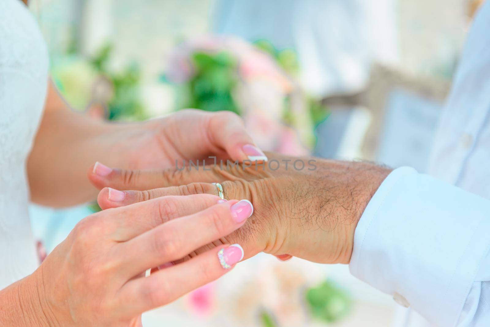 Hands of the newlyweds at the wedding ceremony of dressing the wedding rings, hands close-up.