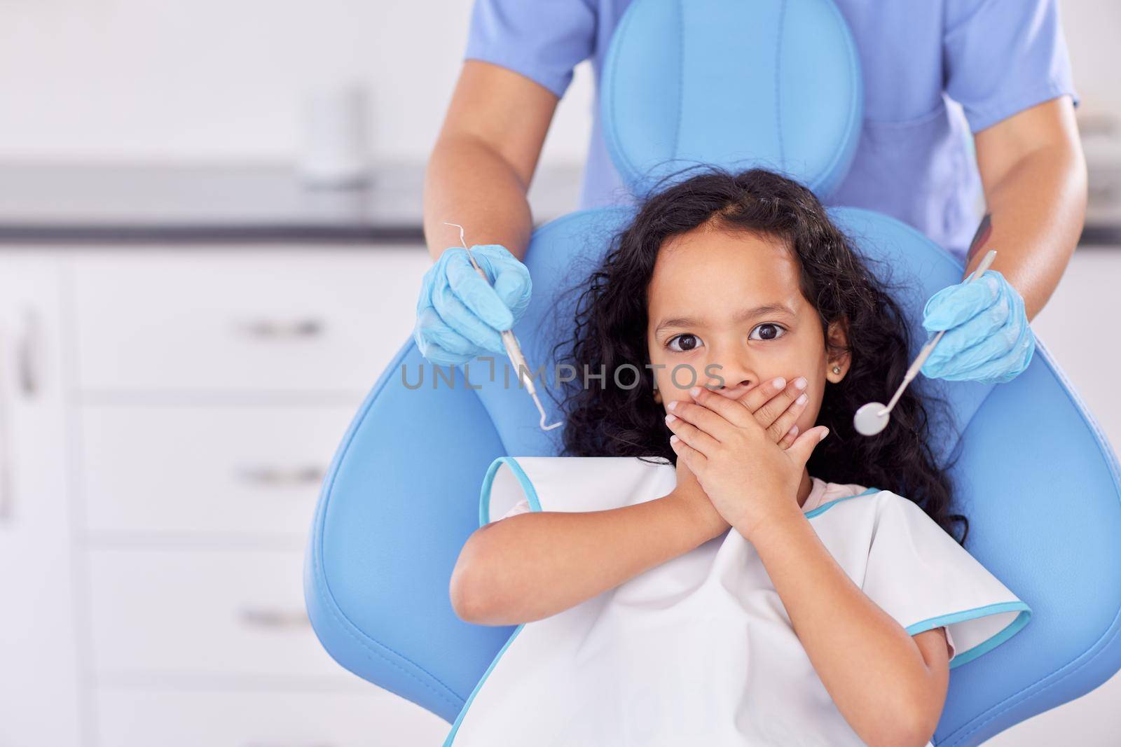 Ready for your tooth repair. Shot of a young girl looking scared while having dental work done on her teeth. by YuriArcurs