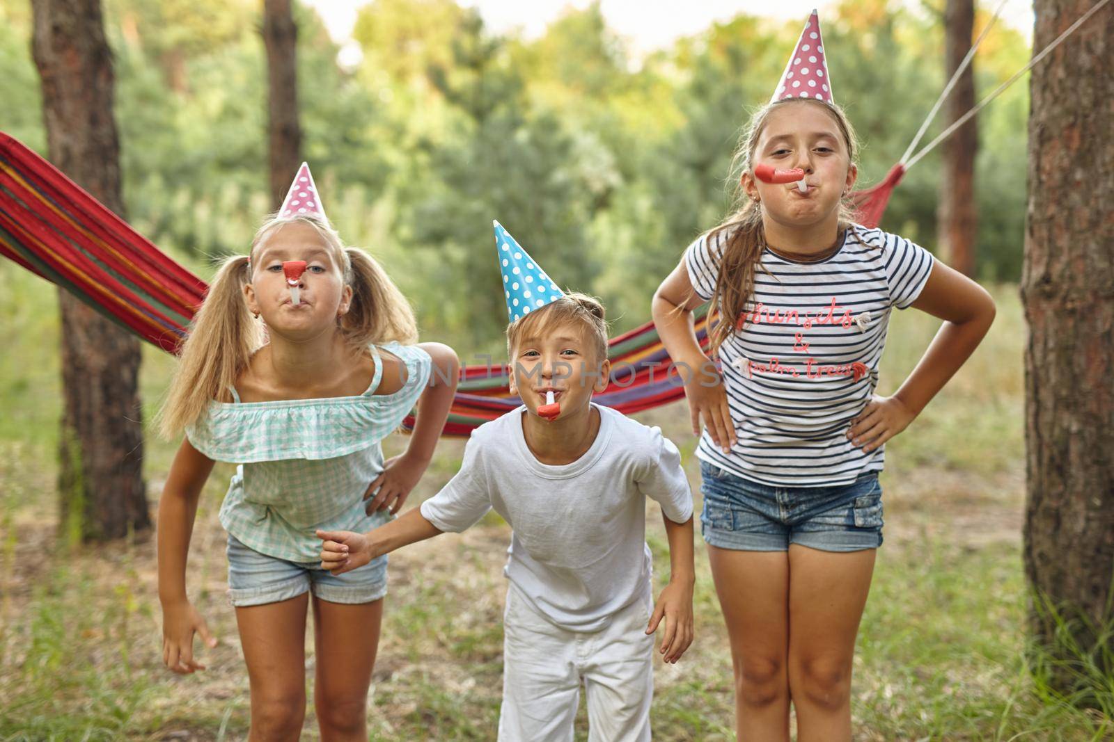 birthday, childhood and celebration concept - happy kids blowing party horns by InnaVlasova