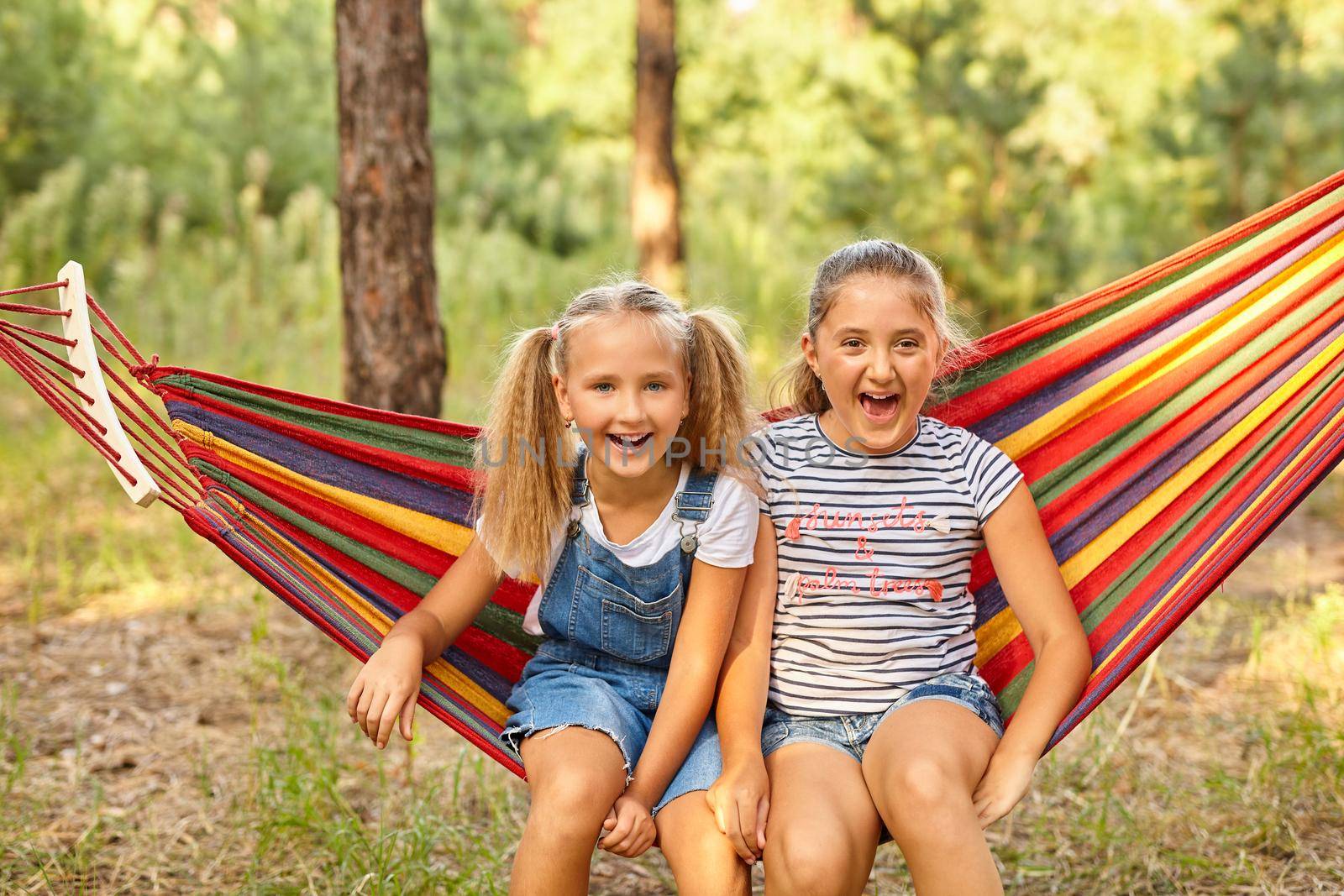 Kids relax in colorful rainbow hammock. cation. Children relaxing. by InnaVlasova