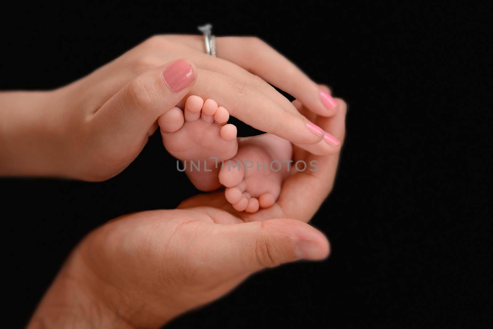 Newborn baby feet and hands of parents. Palms together.