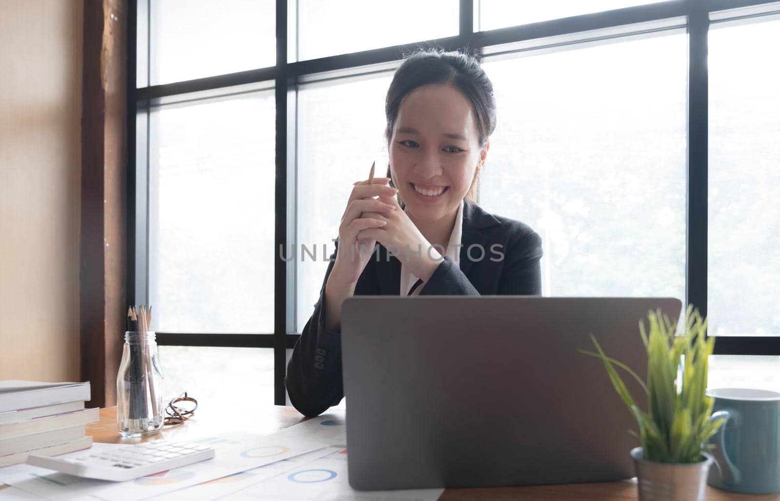 Charming asian businesswoman sitting working on laptop in office..