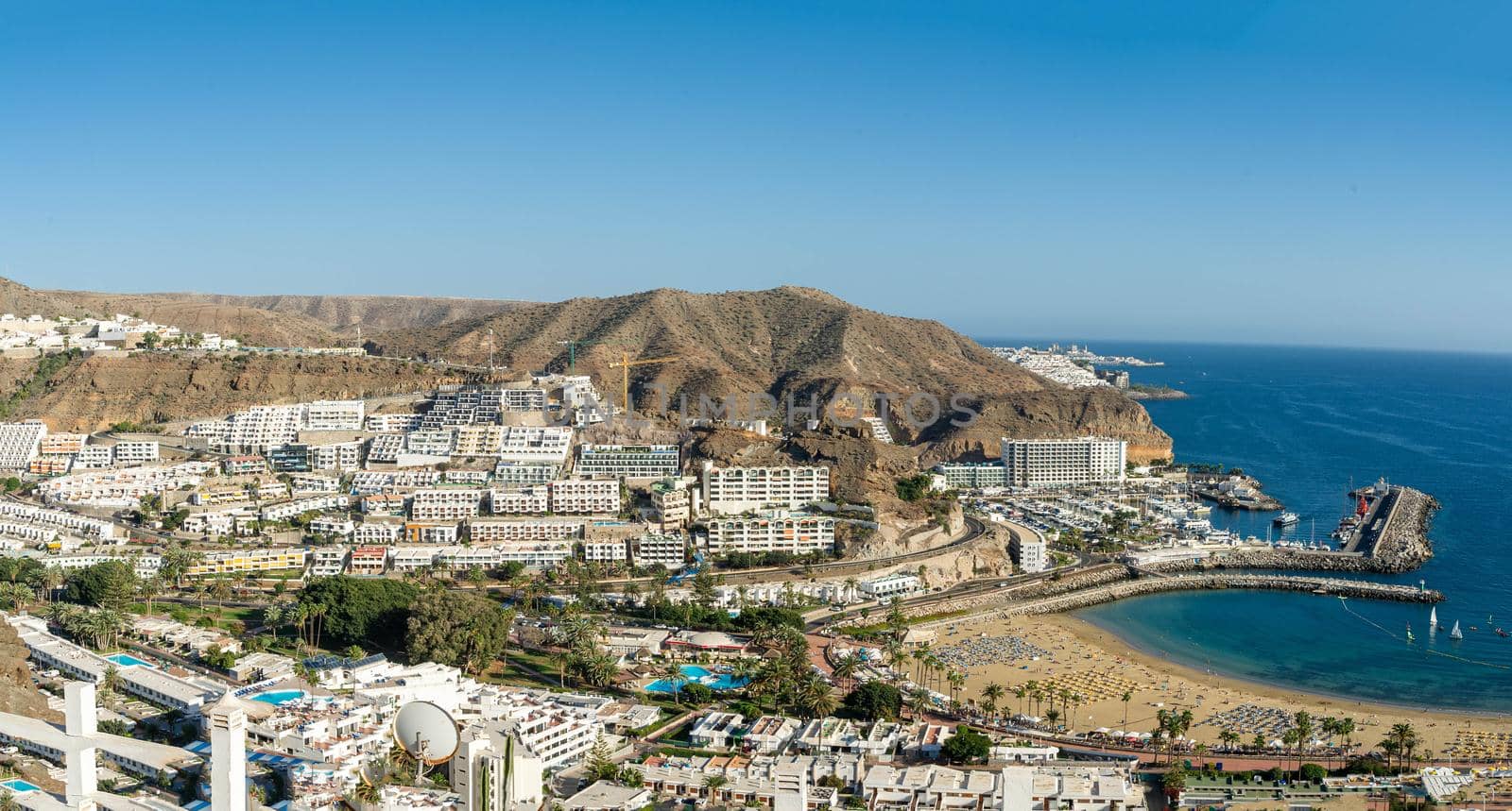 February 2 2022-Panoramic landscape with Puerto Rico village resort and beach on Gran Canaria Spain with yellow sand and volcanic mountains on the background