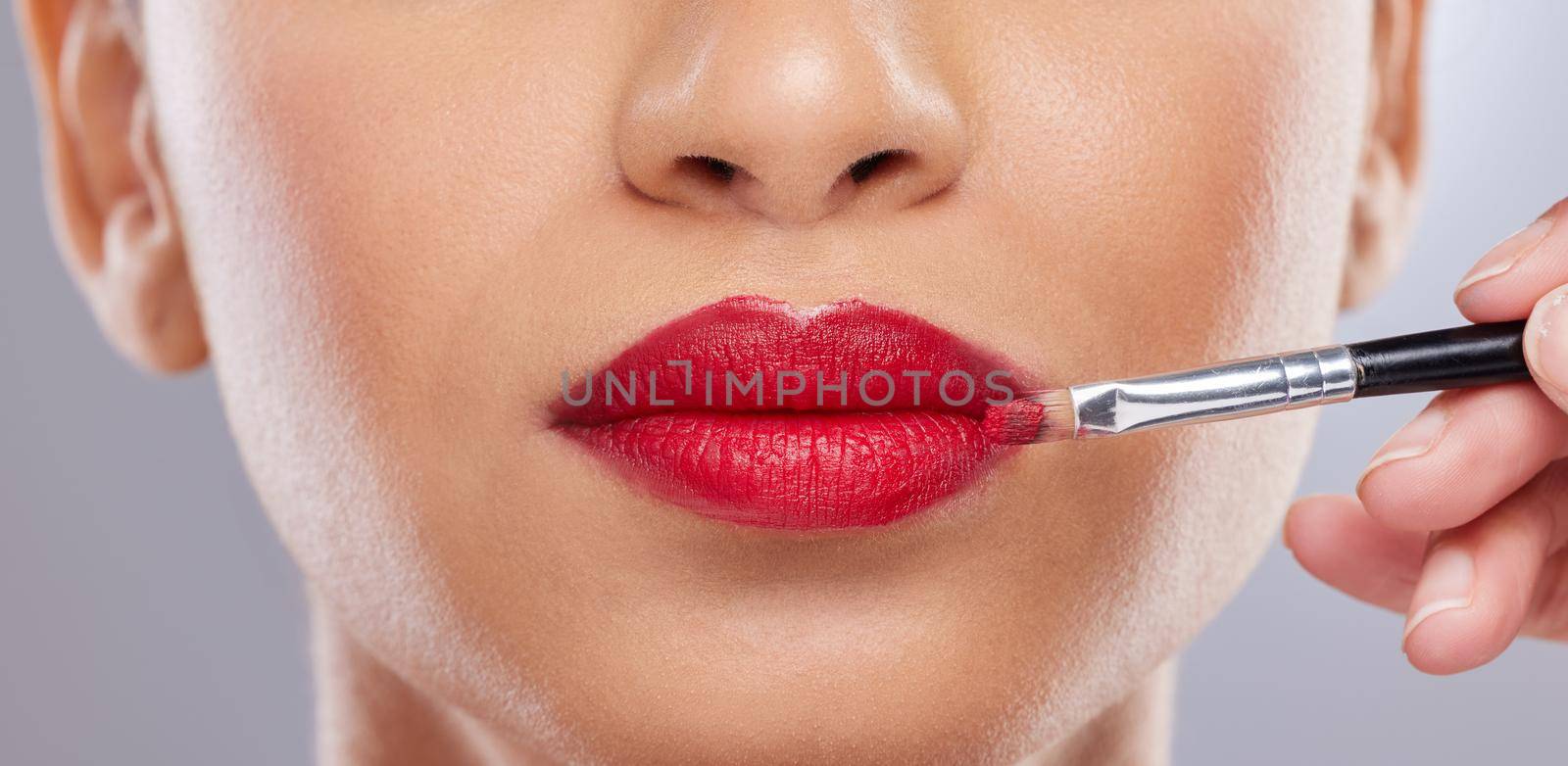 Im all about perfection. Cropped shot of an unrecognisable woman posing in the studio while a makeup artist applies lipstick. by YuriArcurs