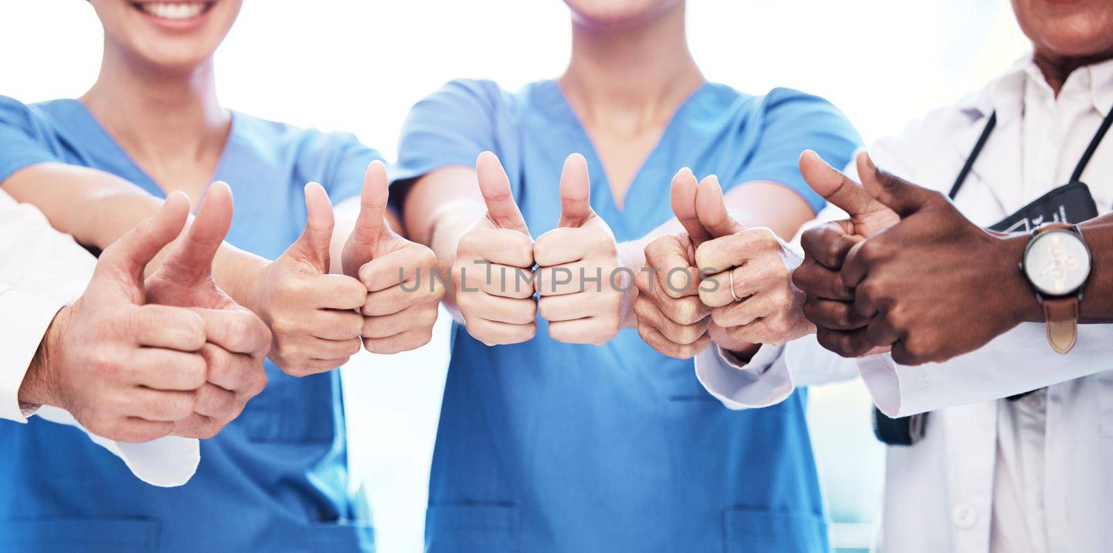 Your health is in the best hands. Shot of a group of unrecognizable doctors showing a thumbs up at a clinic. by YuriArcurs