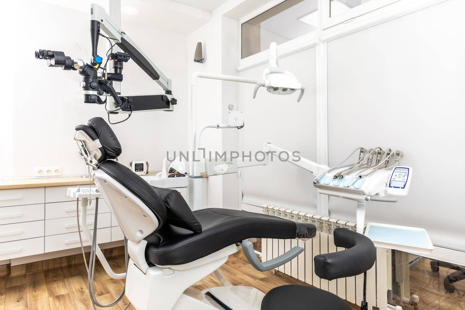 Modern dental cabinet in white colors. Defferent dental equipment, chair, lamp, drill machines. Concept dental treatment with microscope