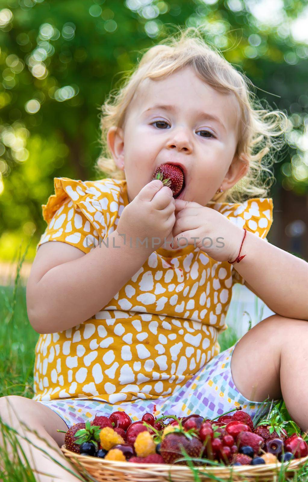 The child eats berries in the garden. Selective focus. by yanadjana