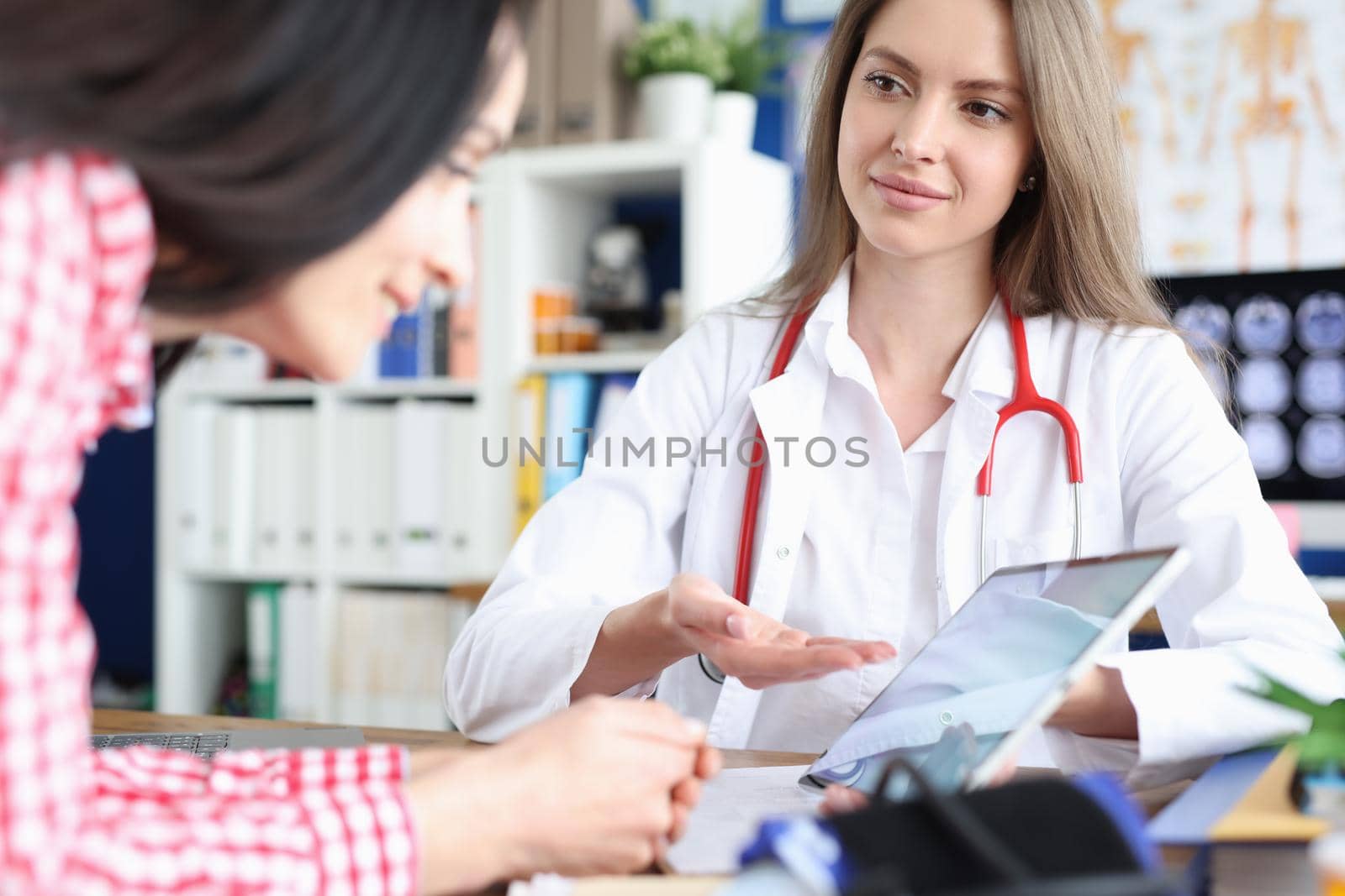 Doctor shows woman on tablet result of medical examination. Viewing ultrasound of baby fetus