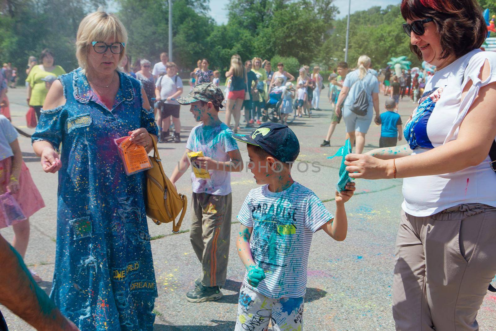 Novokuznetsk, Kemerovo region, Russia - June 12, 2022 :: Happy family with colorful faces painted with holi powder having fun outdoors.