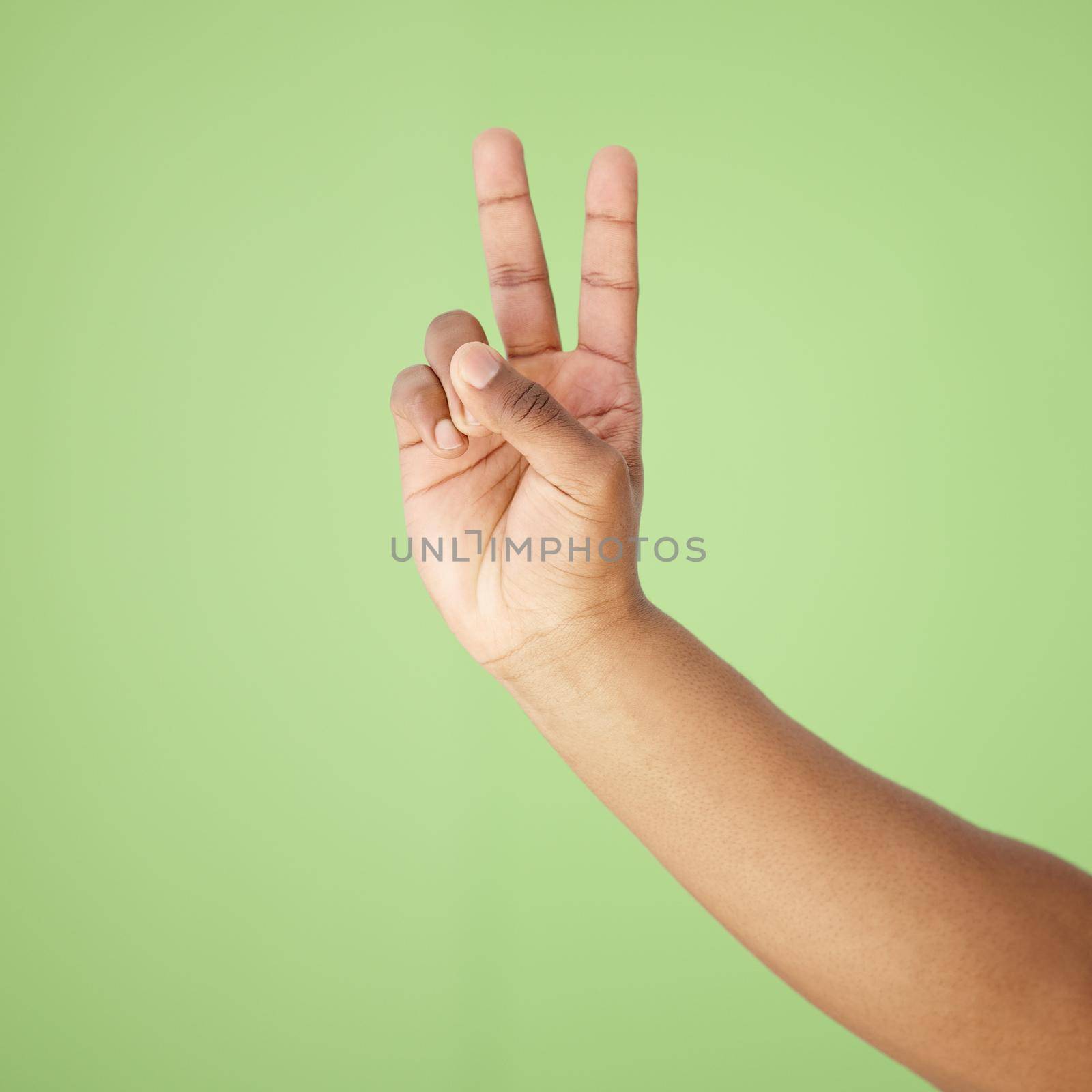 Im outta here. Cropped shot of a hand showing the peace sign against a green background. by YuriArcurs