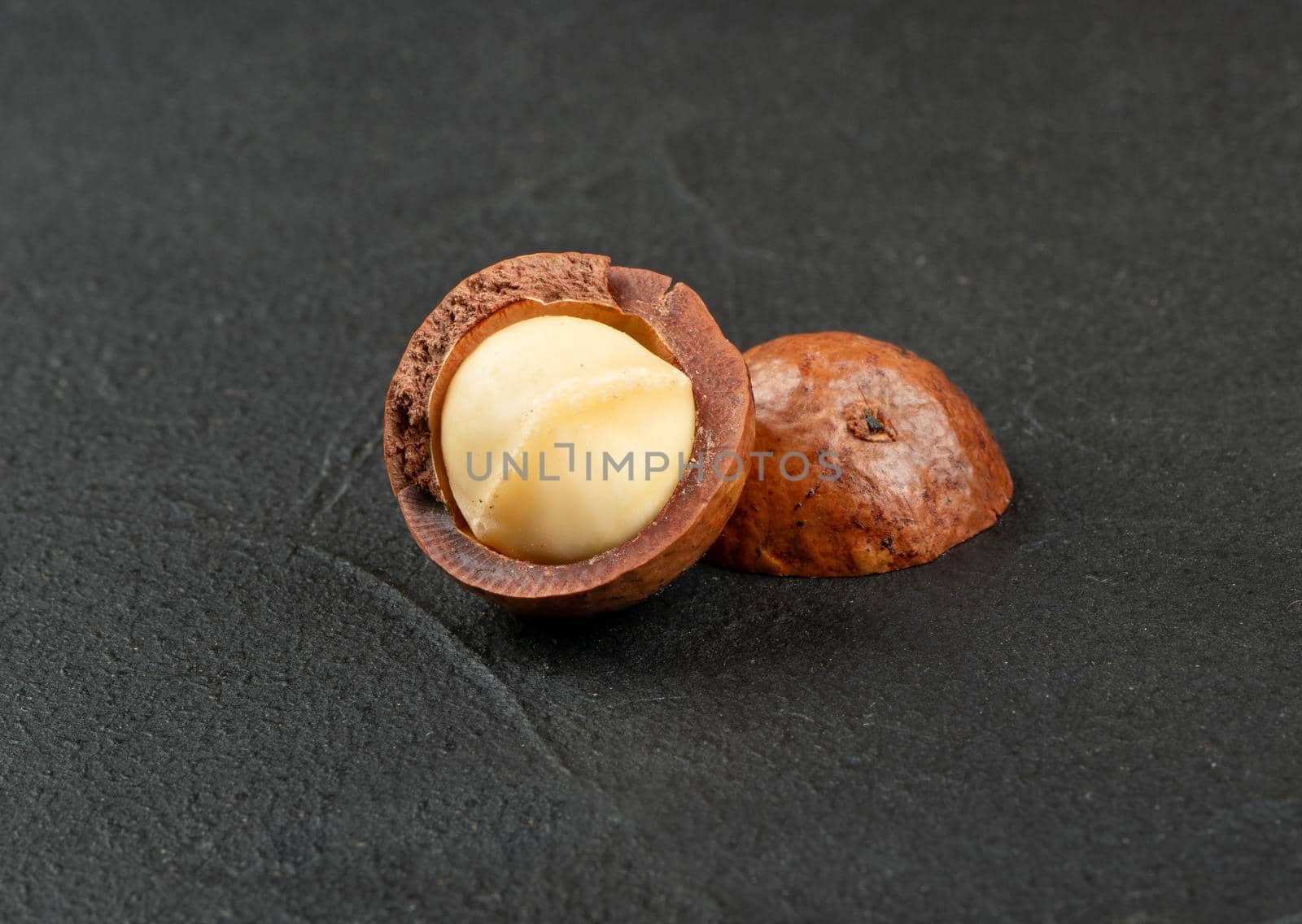 Macadamia nut split into two halves on a dark background