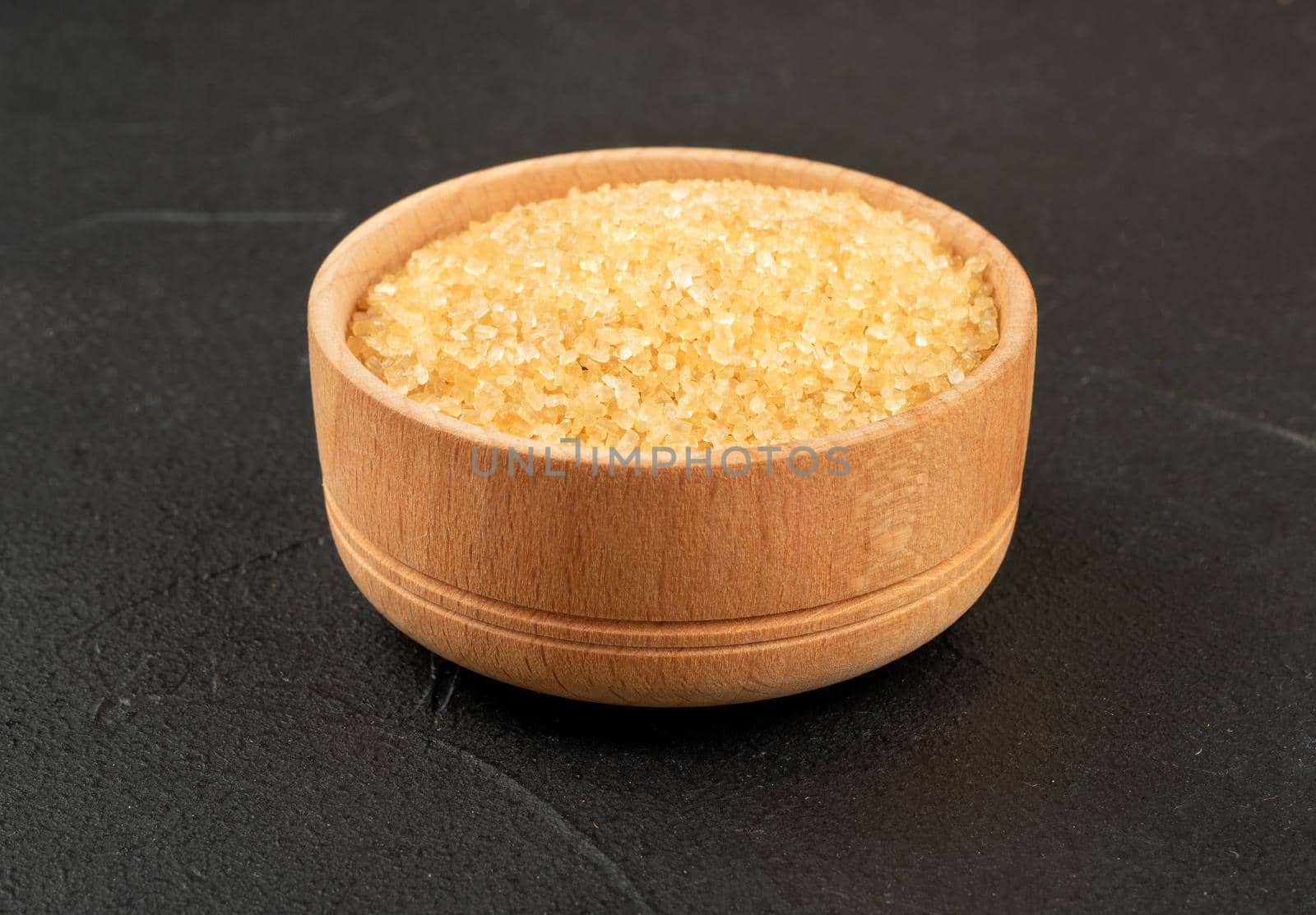 Wooden bowl with brown sugar on a concrete background