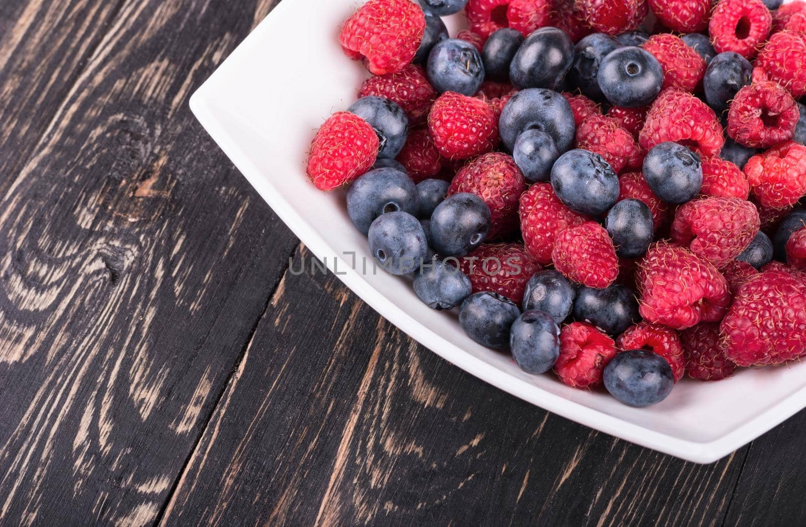 Part plates blueberry and raspberry filling on a dark wooden background