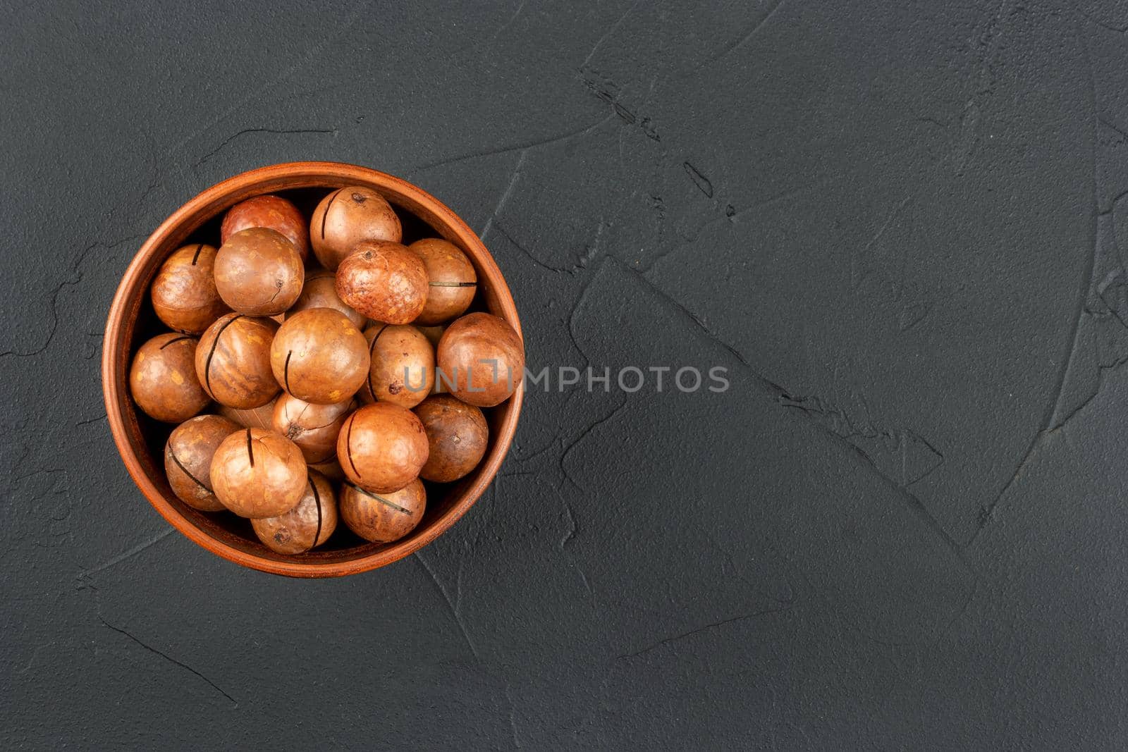 Macadamia nuts in a bowl on an empty concrete background