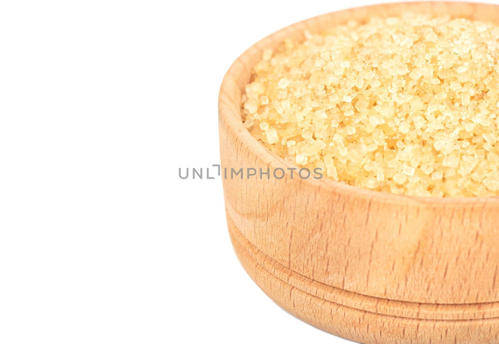 Part of a wooden bowl with brown sugar in close-up on a white background