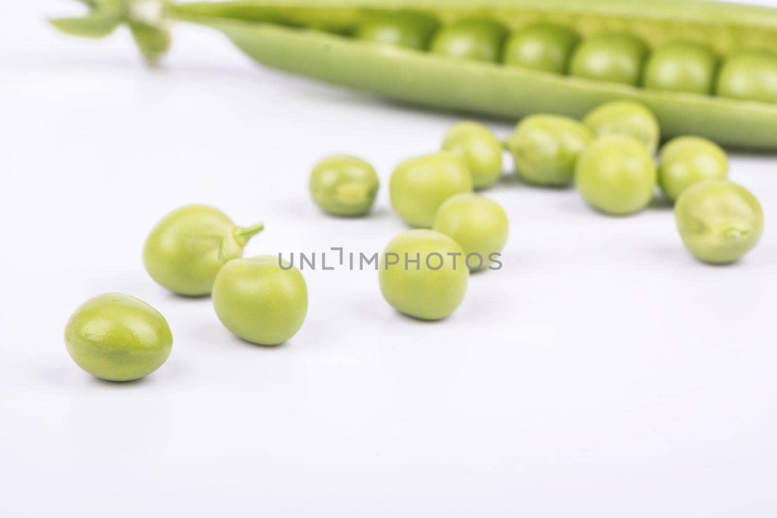 Grains green peas scattered from the pod on a white background