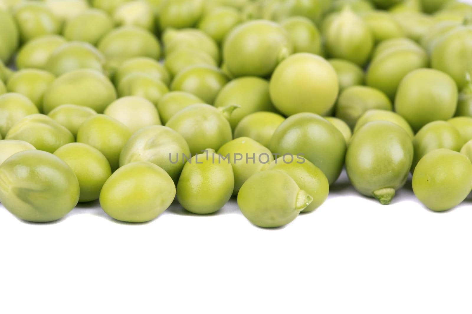 Scattered grains of green peas on a white background closeup