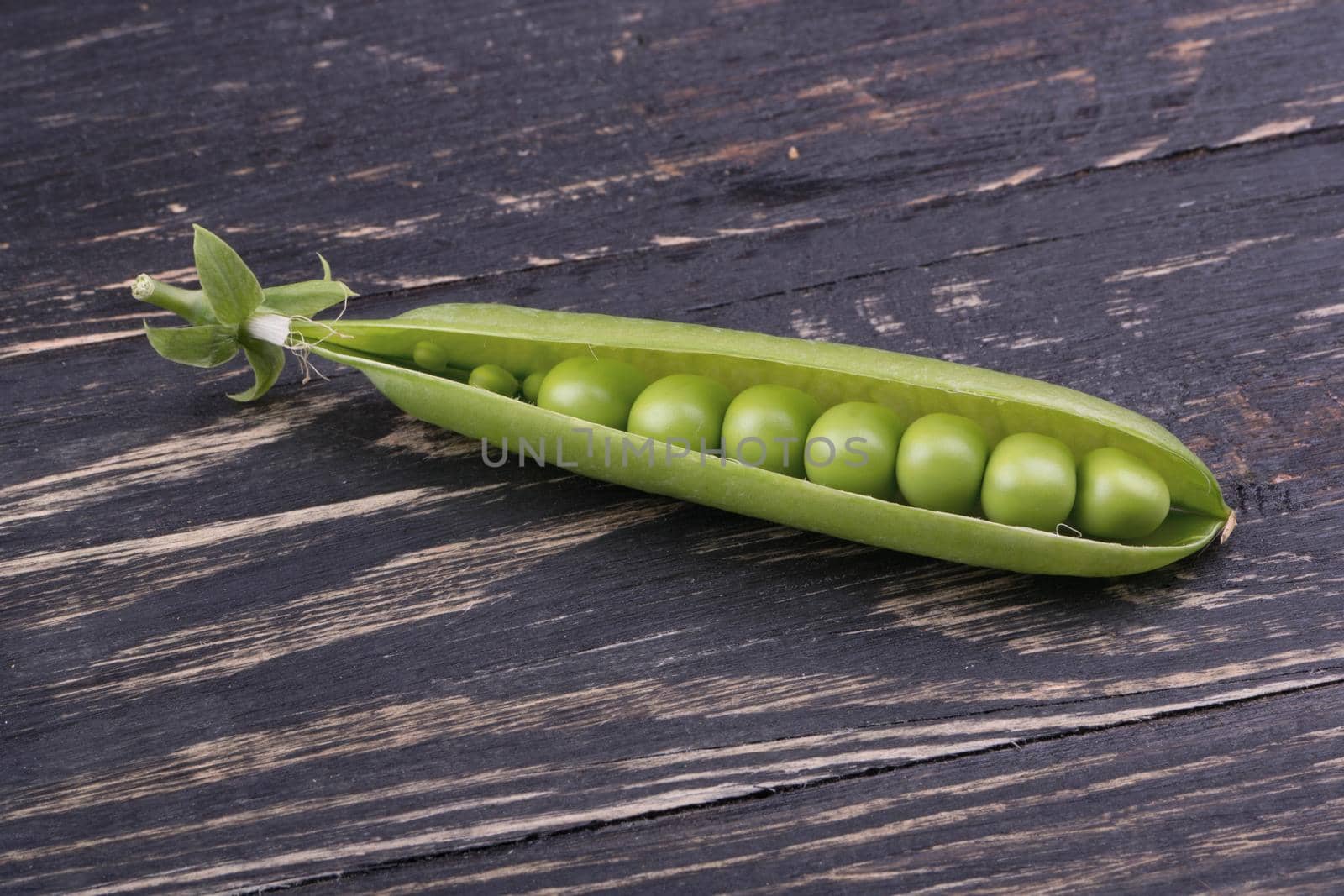 Fresh green peas in open pods with seeds on a wooden background