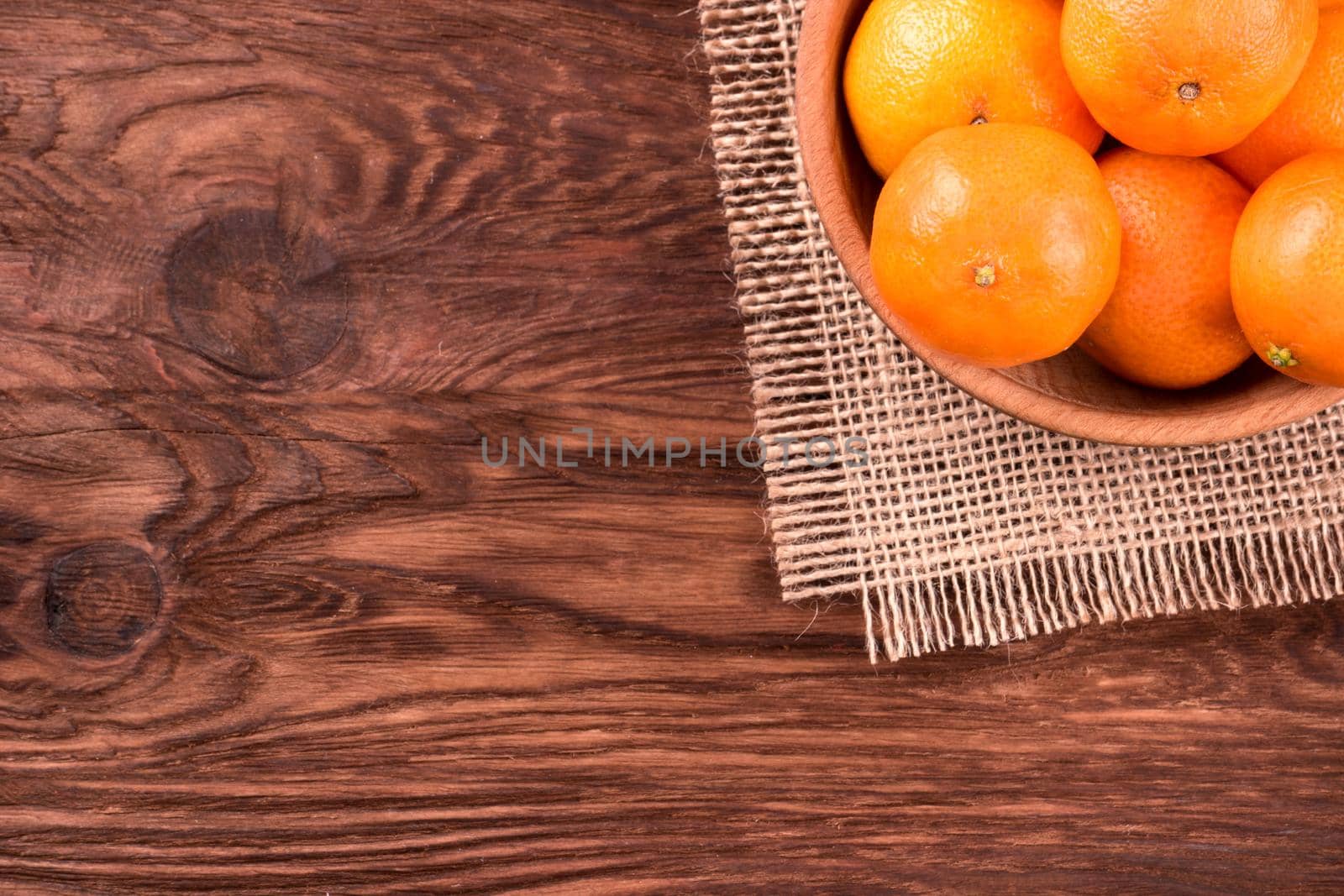 Basket full of ripe mandarins on a wooden background top view