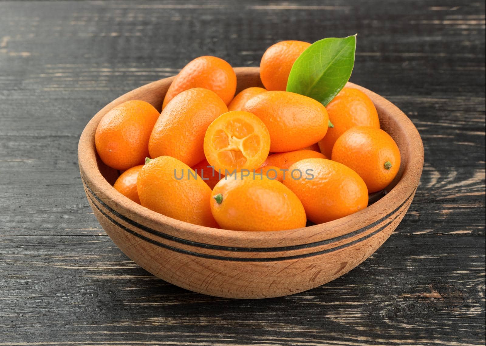 Bowl full of fresh fruit kumquat on a dark table