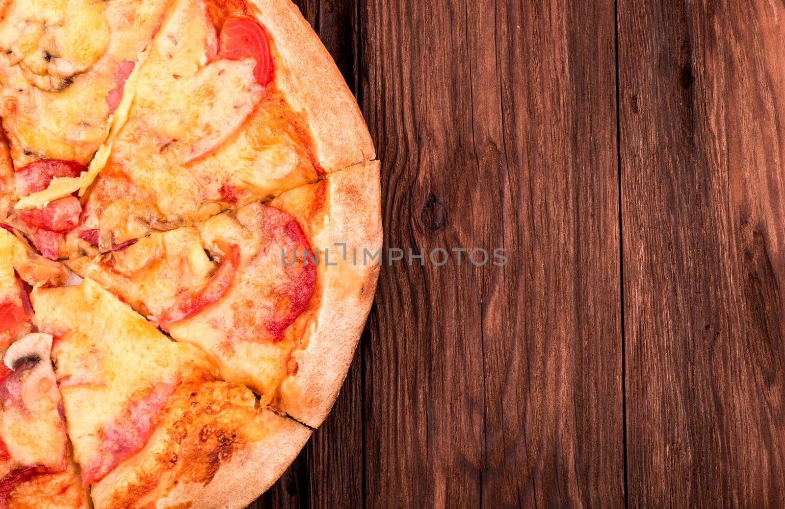 Part fresh pizza with sausage on a wooden background top view